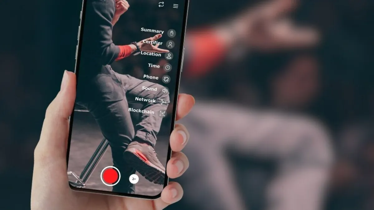 Close-up of a smartphone displaying the SWEAR app interface, capturing video with options for blockchain verification, location, time, and network metadata for digital authentication.